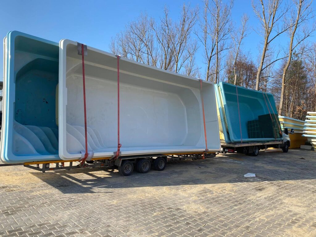 Transport basenów ogrodowych na przyczepie w zimowym krajobrazie