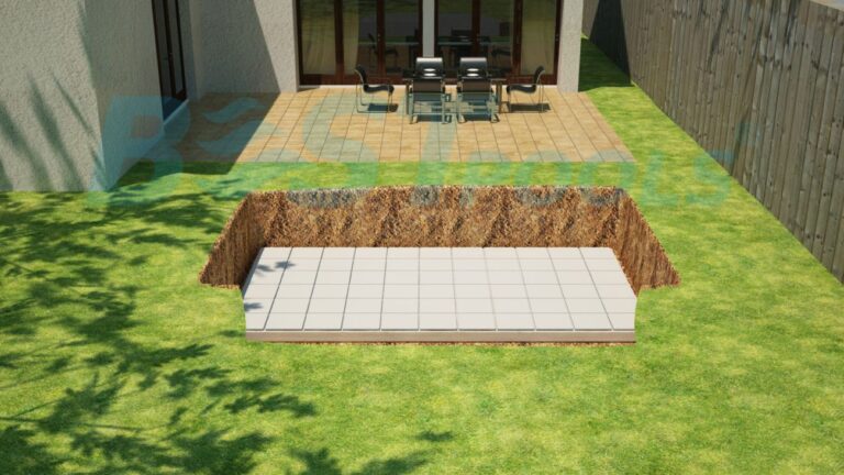 Prostokątny dołek wykopano na trawiastym podwórku w pobliżu patio z zestawem jadalnym. Otwór ma wyłożoną płytkami podstawę i jest otoczony ziemią, obok domu i drewnianego ogrodzenia.