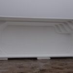 Duża, pusta, biała prostokątna muszla basenowa stoi na ziemi w mglisty dzień, z widocznymi stopniami uformowanymi w jednym rogu.