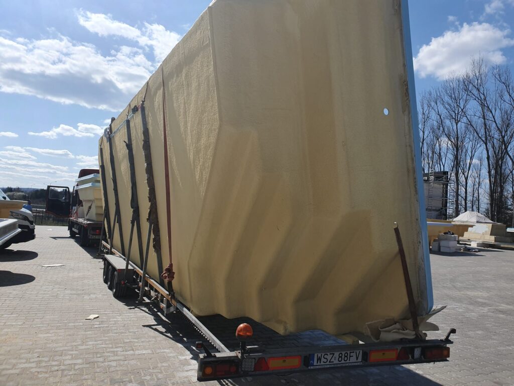 Basen poliestrowy jest zamocowany na płaskiej przyczepie na zewnątrz pod niebieskim niebem z rozproszonymi chmurami.