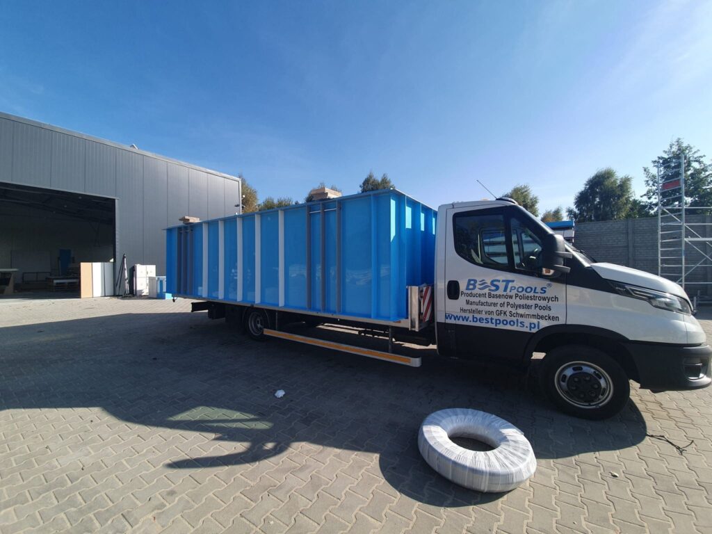 Duży niebieski prostokątny zbiornik jest załadowany na ciężarówkę