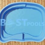 Widok z góry na mały, niebieski basen o nieregularnym kształcie z wbudowanymi schodkami, ustawiony na drewnianym pomoście. Basen jest czysty i pusty z wyjątkiem wody, a logo BEST POOLS jest nałożone na obraz.