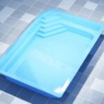 Prostokątny, jasnoniebieski basen z geometrycznymi stopniami w jednym rogu.