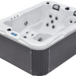 Prostokątna, nowoczesna wanna z hydromasażem z białym wnętrzem, szarymi panelami zewnętrznymi, wbudowanymi siedzeniami, wieloma dyszami wodnymi, zagłówkami i cyfrowym panelem sterowania.